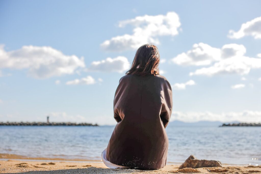 海を眺める女性の後ろ姿の画像